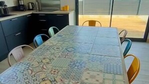 Un comedor con una mesa estampada, sillas y una cocina al fondo.