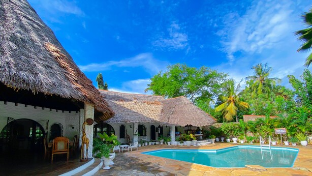 A resort with a pool, thatched-roof structures, and tropical landscaping. - Mfalme Luxury Villas (Mtwapa)