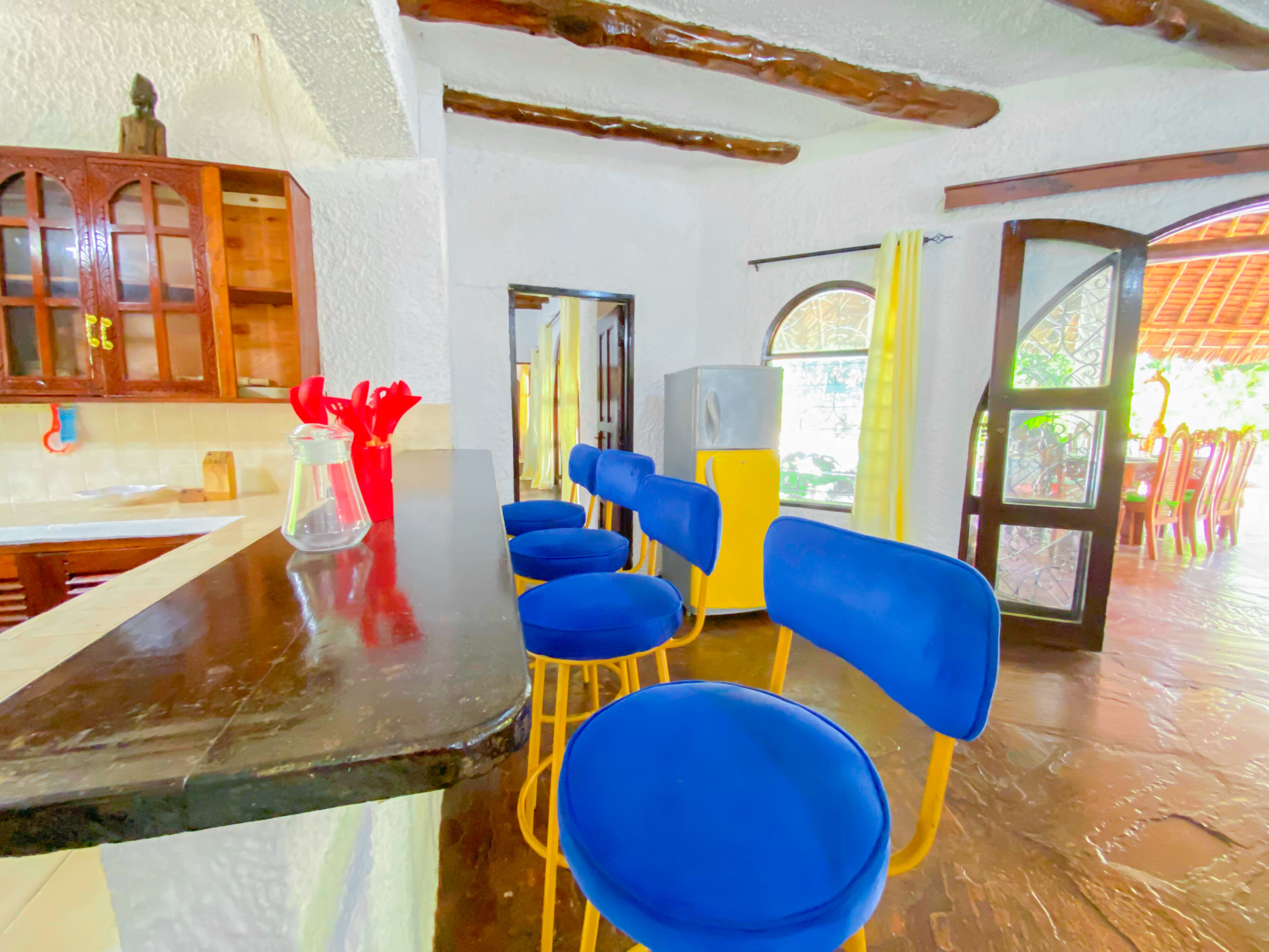 A dining area with blue chairs, a wooden counter, and a yellow refrigerator.