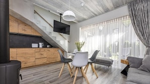 A modern kitchen with a built-in stove, wooden cabinets, and a flat-screen TV. - Apartment In The Forest (Palanga)