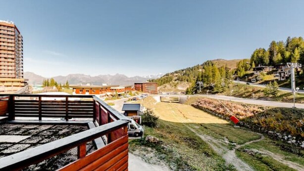 Un hotel con vista a un paisaje montañoso, un área de estacionamiento y un edificio con techo rojo.