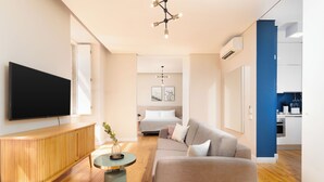 A modern living room with a flat-screen TV, a wooden cabinet, a round coffee table, and a sofa. - Limehome Lisbon Rua do Arsenal (Lisbon)
