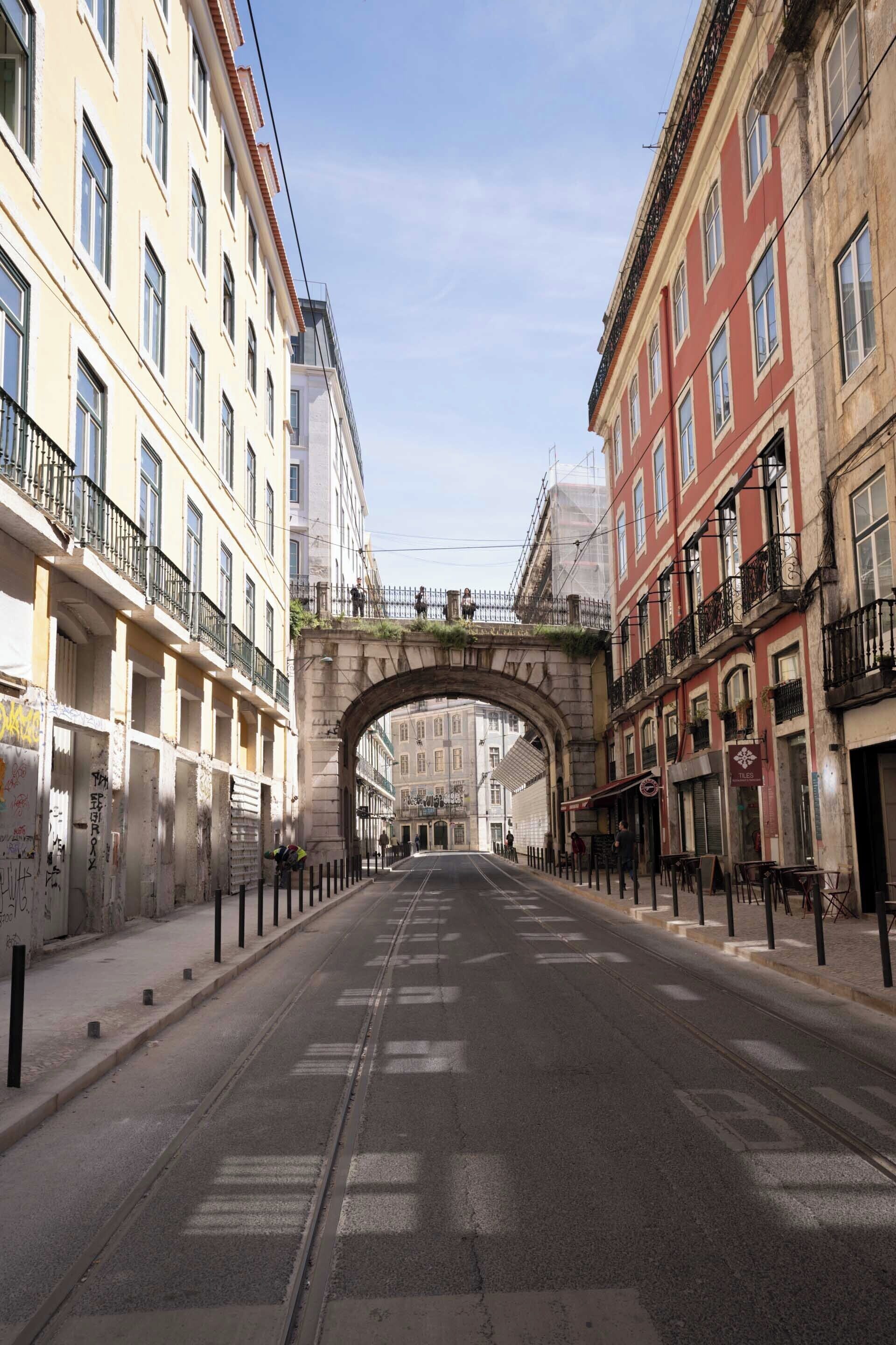 Una calle flanqueada por edificios, un arco y un cielo despejado.