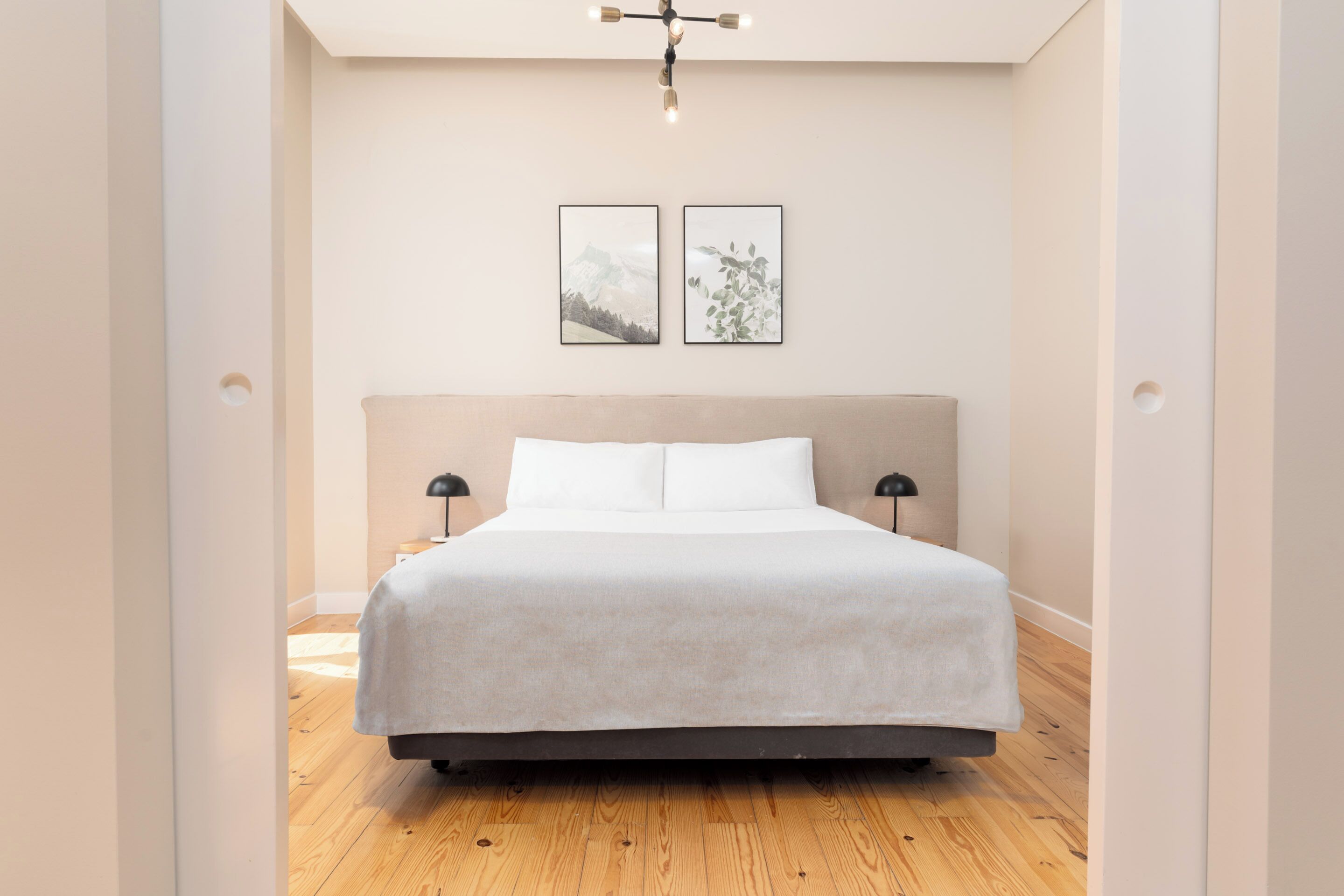 A modern bedroom with a large bed, two bedside tables, and a ceiling light fixture.