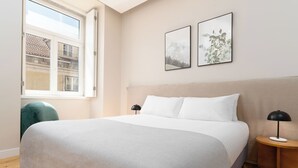 A modern bedroom with a large bed, a window, and two framed pictures on the wall. - Limehome Lisbon Rua do Arsenal (Lisbon)