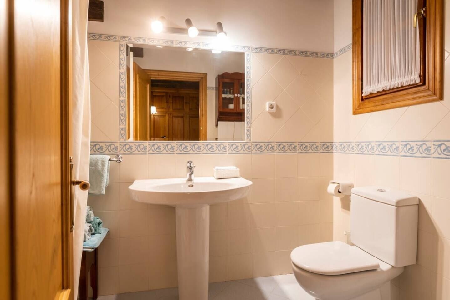 Et badeværelse med en hvid vask, toilet og spejl.