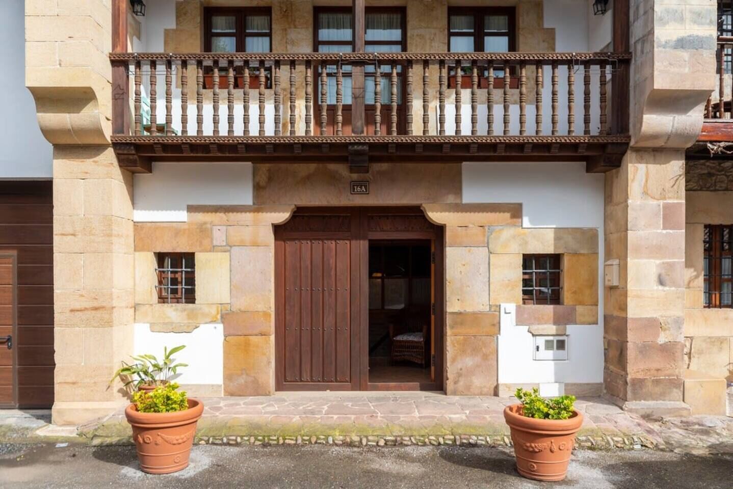 Ein Gebäude mit einem hölzernen Balkon, einer braunen Tür und zwei Blumentöpfen.