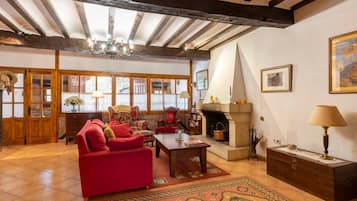 Una sala de estar acogedora con chimenea, vigas de madera y un amplio ventanal.