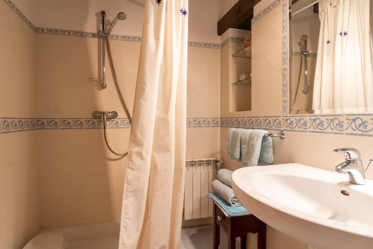 Een badkamer met een douche, een wastafel en een handdoekhouder.