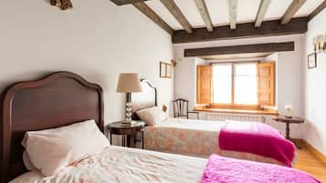 Une chambre avec deux lits, une fenêtre avec des volets, une petite table avec une lampe et une chaise.