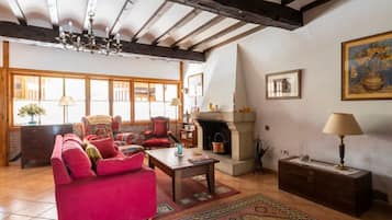 A traditional living room with a fireplace, a sofa set, and a large window.