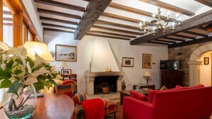 Un salon chaleureux avec une cheminée, un canapé rouge et des poutres en bois au plafond.
