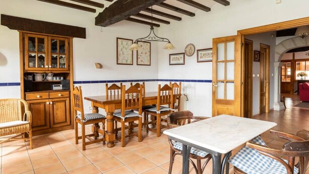 Un coin repas avec une table et des chaises en bois, un buffet avec des portes en verre et un sol carrelé.