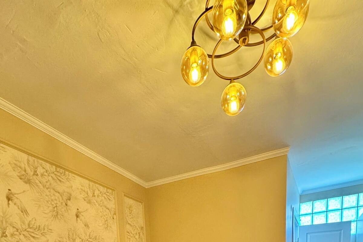 Een slaapkamer met een groot bed, witte lakens en een kroonluchter.