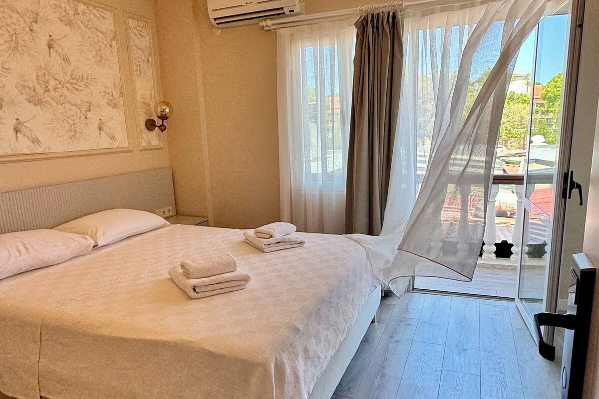 Hotelkamer met een groot bed, een plafondlamp, een airconditioner en uitzicht door een raam met gordijnen.