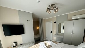 Een moderne slaapkamer met een bed, nachtkastje, televisie, kledingkast en een spiegel.