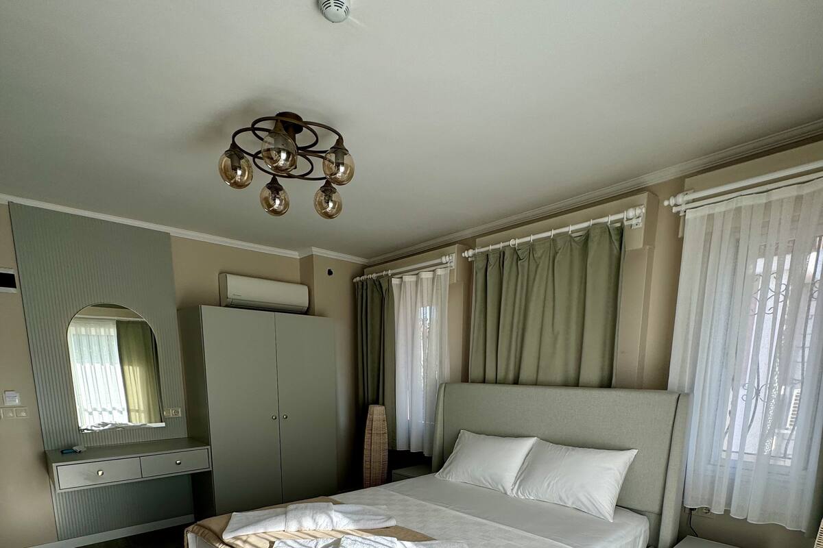 Een slaapkamer met een groot bed, een kledingkast, een nachtkastje en een lamp.