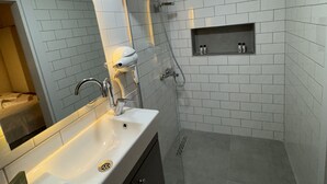 Een moderne badkamer met een wit wastafelmeubel, spiegel en douchehoek.