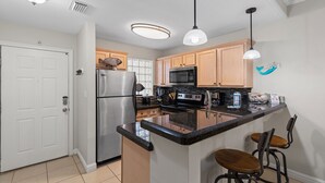 A modern kitchen with a central island, stainless steel appliances, wooden cabinets, and pendant lighting.
