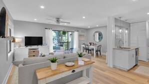 Una sala moderna con sofá, televisor y comedor.