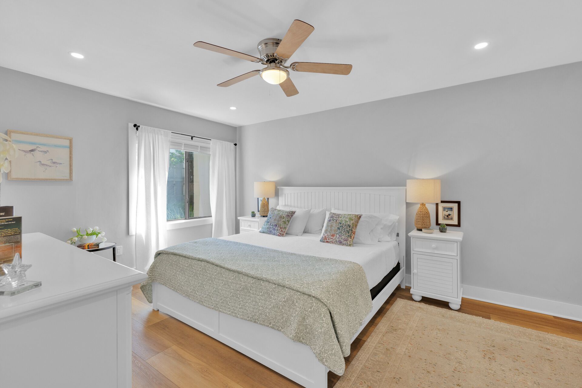 A bedroom with a bed, nightstands, a ceiling fan, and a window with curtains.