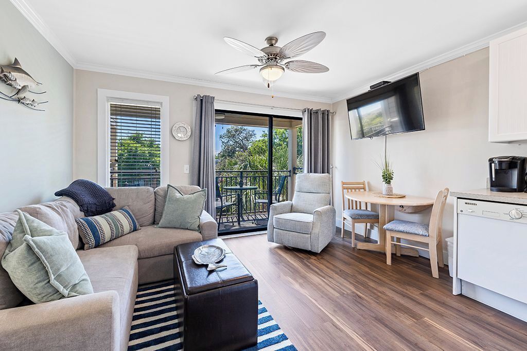 Een moderne woonkamer met een bank, fauteuils, een salontafel, een televisie en een balkon met uitzicht.