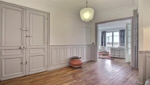 A spacious room with wooden flooring, white walls, a large wardrobe, and a hanging light fixture. - RIGHT AROUND THE CORNER, NEAR EVERYWHERE YOU WANT TO BE–SAINT GERMAIN (Paris)