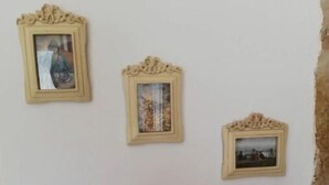 Three framed pictures on a wall, with a mobile phone mounted below them.