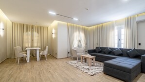 A modern living room with a grey sectional sofa, a white table, and two white chairs. - Golden House  (New Cairo)