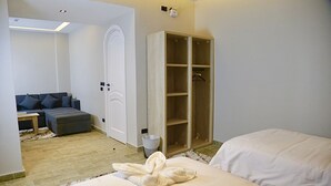A bedroom with a bed, a sofa, a wooden wardrobe, and a small table. - Golden House  (New Cairo)