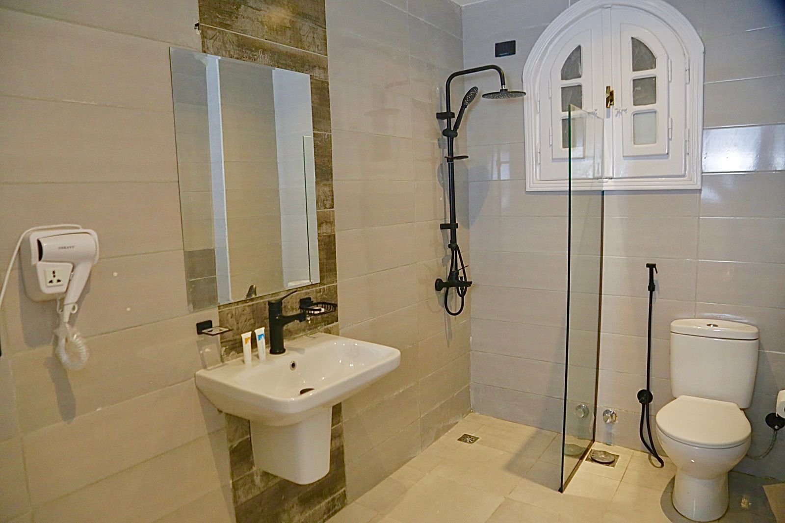 A bathroom with a sink, mirror, shower, and toilet.