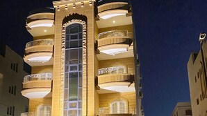 A multi-story building with balconies, a central entrance, and a car parked in front. - Golden House  (New Cairo)