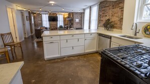 A modern kitchen with a large island, white cabinetry, and a black stove. - 2 suites in one, pet-friendly, near Lake Michigan (Michigan City)