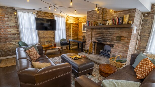 A cozy living room with a brick fireplace, leather sofas, and a flat-screen TV. - 2 suites in one, pet-friendly, near Lake Michigan (Michigan City)