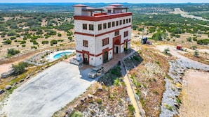 A multi-story building with a pool, surrounded by a natural landscape.
