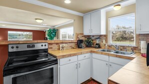 A kitchen with white cabinets, a black stove, a sink, and a window with blinds. - Experience ranch living at Lighthouse Hill Ranch - Red House on 2001 acres! (Johnson City)