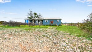 A single-story house with a blue exterior and a front porch. - Hilltop Ranch Stay on 2,001 Acres | Shared Pool, Hot Tub & Trails (Johnson City)