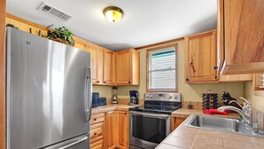 A modern kitchen with wooden cabinets, stainless steel appliances, and a window with blinds. - Hilltop Ranch Stay on 2,001 Acres | Shared Pool, Hot Tub & Trails (Johnson City)