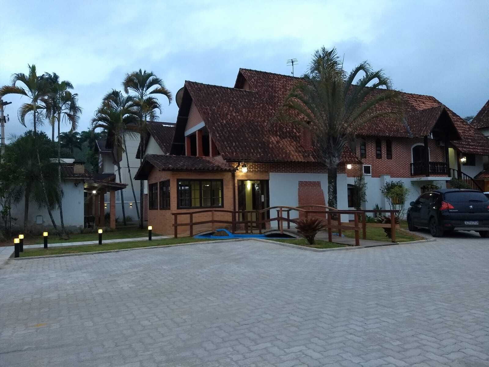A two-story building with a tiled roof, a wooden deck, and a paved driveway.