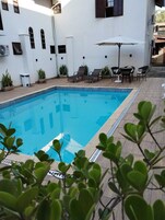 Una piscina techada, una piscina al aire libre, sombrillas