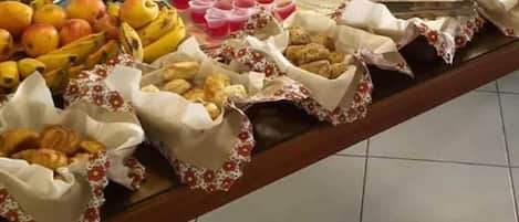 Una mesa de buffet con diversos alimentos, como frutas, pasteles y bebidas.