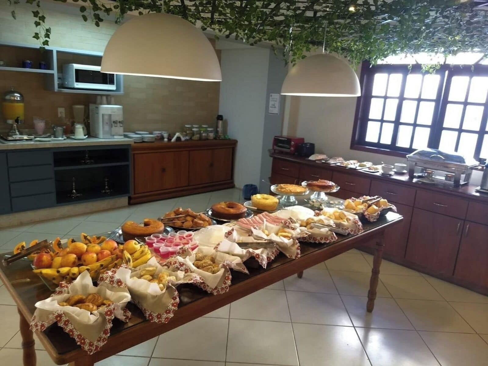 Una mesa de buffet con diversos alimentos y una zona de cocina con electrodomésticos y armarios.