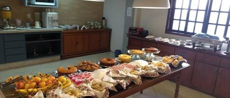 Una mesa de buffet con diversos alimentos y una zona de cocina con electrodomésticos y armarios.