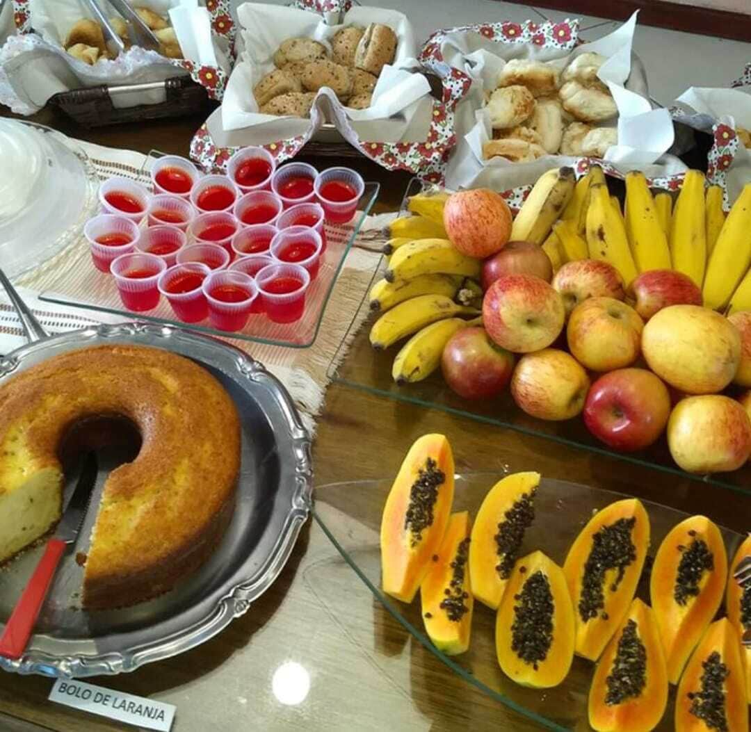 En buffet med et udvalg af mad, herunder kage, frugter som bananer og æbler, samt papaya.