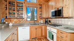 A kitchen with wooden cabinets, a stainless steel sink, a stove, and a microwave. - Lakeside Chalet - Luxury Retreat on Grand Lake w/ Dock & Kayaks (Grand Lake)