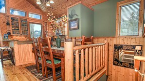 A wooden cabin interior with a dining area, kitchen, and a view of the mountains. - Lakeside Chalet - Luxury Retreat on Grand Lake w/ Dock & Kayaks (Grand Lake)