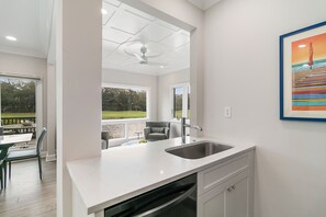 A modern kitchen with a large island, a built-in dishwasher, and a view of a patio with outdoor furniture. - Views and location, great villa in Turtle Point (Kiawah Island)