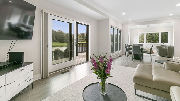 A modern living room with a flat-screen TV, a vase with flowers, and a beige sofa. - Views and location, great villa in Turtle Point (Kiawah Island)