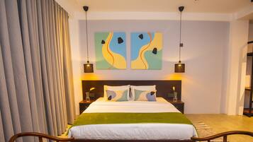 A modern bedroom with a large bed, two side tables, abstract wall art, and a patterned rug.