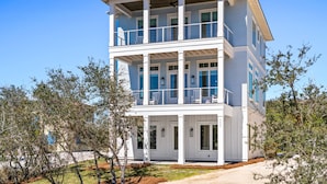 A two-story beachfront house with a balcony, large windows, and a covered porch. - The Boat House at Kiva Dunes (Gulf Shores)